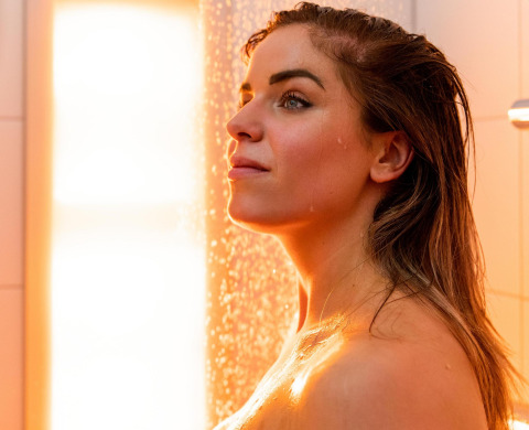 Kvinde nyder et afslappende brusebad med varmt lys ved Wellness Lodge på Hof van Salland, Holland.