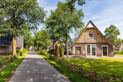 Casa tiny Wellness Lodge XL en Hof van Salland, Países Bajos, rodeada de jardines y naturaleza bajo el sol.