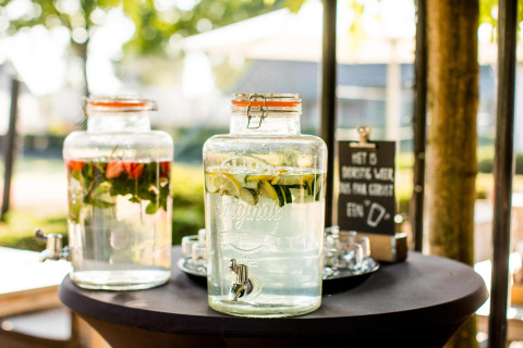 Due dispenser di vetro con acqua aromatizzata su un tavolo in una tiny house con bicchieri accanto.