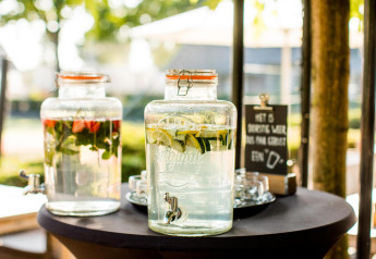 Dos dispensadores de vidrio con agua infusionada en una mesa de una tiny house, con vasos al lado.
