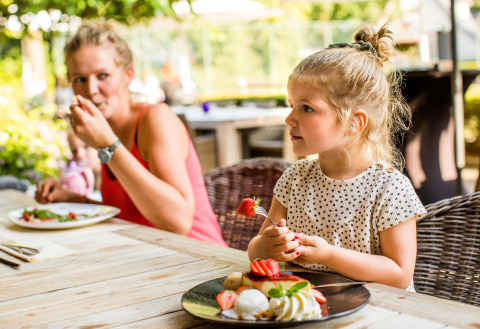 Una bambina mangia un dessert con una donna a un tavolo esterno presso Wellness Lodge XL, Hof van Salland.