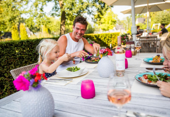 Familia disfrutando de una comida al aire libre en Wellness Lodge XL en Hof van Salland, Países Bajos, rodeada de naturaleza.