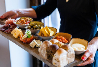 Una bandeja de charcutería con quesos, embutidos y pan en Wellness Lodge XL, Hof van Salland, Países Bajos.