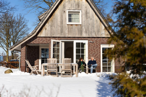 Paar sitzt vor dem Wellness Lodge XL im Hof van Salland, Niederlande, im verschneiten Winter.
