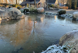 Tiny house Wellness Lodge XL at Hof van Salland, Netherlands, with frosty pond and garden in winter.