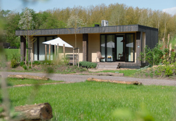 Moderne Lodge Culinary ved Resort de Parel, omgivet af grønne marker og skov i Holland på en solskinsdag.