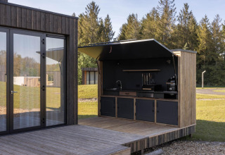 Outdoor kitchen at Lodge Culinary, Resort de Parel, Netherlands, featuring modern wood and glass design.