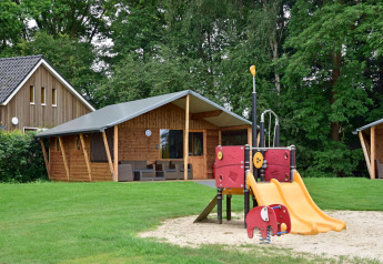 Aire de jeux avec toboggan devant les cabanes en bois de Cabin au Camping de Koeksebelt, Pays-Bas, proche forêt.