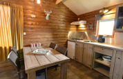 Gezellig houten cabin-interieur met eettafel, keuken en raam bij Camping de Koeksebelt in Nederland.