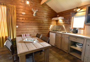 Intérieur de cabane confortable avec murs en bois, table à manger et cuisine au Camping de Koeksebelt, Pays-Bas.