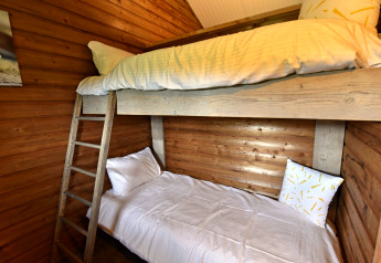 Chambre chaleureuse avec lits superposés et murs en bois à la cabane du Camping de Koeksebelt, Pays-Bas.