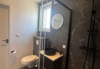 Baño moderno en Forest villa lodge con inodoro suspendido, lavabo negro, ducha y decoración elegante.