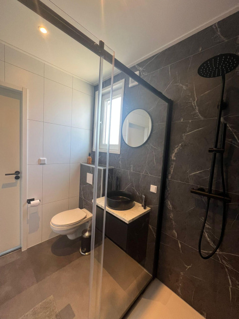 Baño moderno en Forest villa lodge con inodoro suspendido, lavabo negro, ducha y decoración elegante.