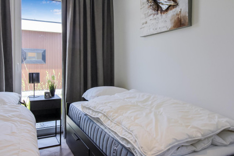 Dormitorio doble en Forest villa lodge con dos camas, mesa de noche, lámpara y ventana con vista al jardín.