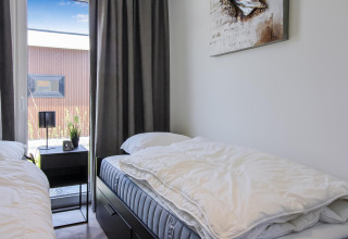 Dormitorio doble en Forest villa lodge con dos camas, mesa de noche, lámpara y ventana con vista al jardín.