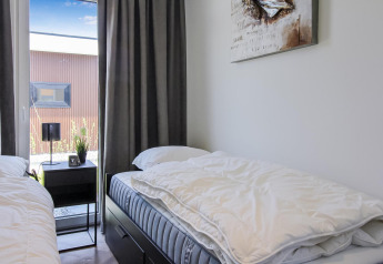 Schlafzimmer der Forest villa Lodge mit zwei Einzelbetten, Nachttisch, Lampe und Blick in den Garten.