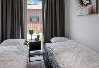 Moderne dobbeltværelse på Forest villa-lodge med to enkeltsenge, natbord og stort vindue.
