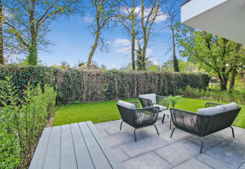 Moderne terras bij Forest villa met comfortabele tuinset, gazon en uitzicht op groene begroeiing.