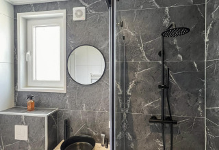Moderne badeværelse på Forest Villa med sort vask, brusebad og marmorerede vægge i grå toner.