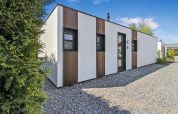 Moderna cabaña Forest villa en Uniq Leisure, Países Bajos, fachada blanca y detalles en madera, día soleado.