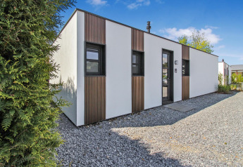 Moderna cabaña Forest villa en Uniq Leisure, Países Bajos, fachada blanca y detalles en madera, día soleado.
