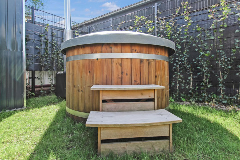 Bañera de madera con bandas metálicas y escalones en la Forest villa de Uniq Leisure, Países Bajos.
