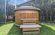 Houten hottub met metalen ringen en traptreden op gras bij Forest villa van Uniq Leisure, Nederland.