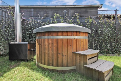 Udendørs træhot tub med låg og trappe ved Forest villa på Uniq Leisure i Nederlandene, solrig dag