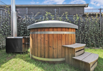 Buiten houten hottub met deksel en trap bij Forest villa van Uniq Leisure in Nederland, zonnige dag