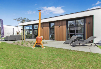 Moderne lodge ved Forest villa Uniq Leisure i Holland med terrasse, liggestole og grøn have foran.