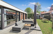 Udendørs opholdsområde ved Eco Lodge hos Uniq Leisure i Holland med sofa, parasol og grøn have.