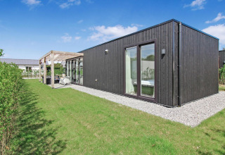 Moderne Eco Lodge på Uniq Leisure i Holland med sort træfacade, store vinduer og en hyggelig have.