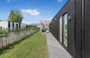 Modern cabin at Eco Lodge at Uniq Leisure, Netherlands, with black façade, garden, and terrace in clear weather.
