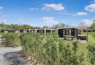 Eco Lodge ved Uniq Leisure i Holland, sorte træhytter med store vinduer, terrasse og have under blå himmel.