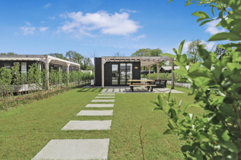 Foto de Eco Lodge en Uniq Leisure, Países Bajos, con césped verde, terraza y arquitectura moderna.