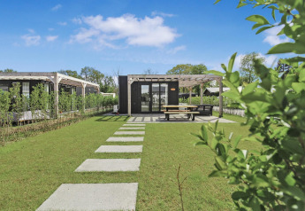 Photo of Eco Lodge at Uniq Leisure in the Netherlands with green lawn, terrace, and modern architecture.