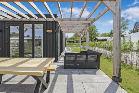 Terraza exterior en Eco Lodge en Uniq Leisure, Países Bajos, con pérgola de madera y zona para sentarse.
