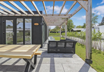 Terraza exterior en Eco Lodge en Uniq Leisure, Países Bajos, con pérgola de madera y zona para sentarse.