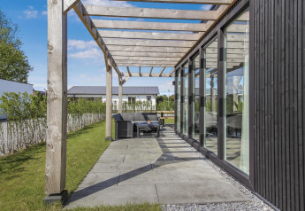 Modern patio with glass walls and a wooden pergola at Eco Lodge at Uniq Leisure, Netherlands, sunny day.