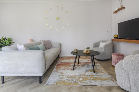 Sala moderna en Eco Lodge de Uniq Leisure en los Países Bajos, con muebles claros y reloj de pared grande.