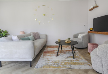 Modern living room at Eco Lodge at Uniq Leisure, Netherlands, with light furniture and a large wall clock.