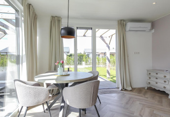 Lyst og moderne spiseområde i Eco Lodge på Uniq Leisure, med runde borde, komfortable stole og udsigt til haven.