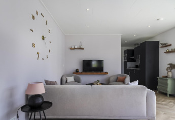 Sala moderna en Eco Lodge en Uniq Leisure, Países Bajos, con decoración elegante y gran reloj de pared.