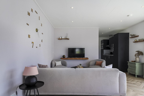 Sala moderna en Eco Lodge en Uniq Leisure, Países Bajos, con decoración elegante y gran reloj de pared.