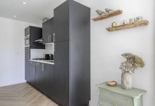 Moderne køkkenindretning i Eco Lodge hos Uniq Leisure, Holland, med sorte skabe og minimalistisk dekoration.