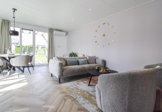 Moderne stue i Eco Lodge ved Uniq Leisure, Holland, med blødt interiør og store vinduer mod haven.