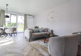 Salón moderno en Eco Lodge de Uniq Leisure, Países Bajos, con decoración cálida y vistas al jardín.