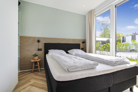 Moderne, lys soveværelse på Eco Lodge ved Uniq Leisure i Holland med store vinduer og udsigt til naturen.