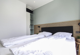 Moderne soveværelse i Eco Lodge på Uniq Leisure, Nederlandene, med dobbeltseng og minimalistisk indretning.