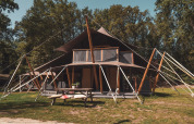 Tienda safari Kings Lodge con jacuzzi en Sandberghe, Países Bajos, rodeada de naturaleza y árboles altos.